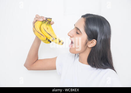 Jungen asiatischen Mädchen, dass Reife frische organische gelbe Banane auf weißem Hintergrund, frischen Früchten und Health Concept - Bild Stockfoto