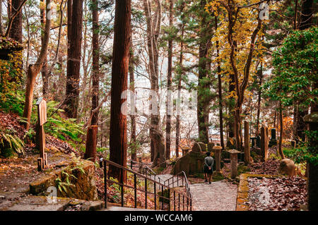 DEC 3, 2018 Yamagata, Japan - Tourist auf Yonsunmichi Pfad in Pinienwald mit Abendlicht an yamadera Risshaku ji-Tempel im Herbst. Stockfoto