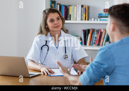 Ärztin Anhören von jungen erwachsenen Patienten im Krankenhaus Stockfoto