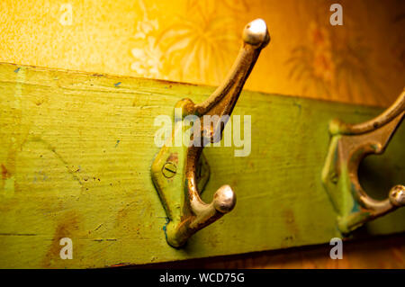 Alte Kleiderhaken Kleiderbügel für Kleidung auf einem hölzernen green Board. Stockfoto