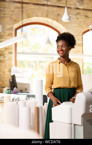 Motivierte Mitarbeiter stehen in der Nähe von Rollen Papier im Büro Stockfoto