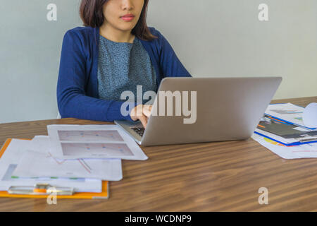 Junge Frau konzentriert sich auf die Arbeit mit Laptop neben Dokumente Stockfoto