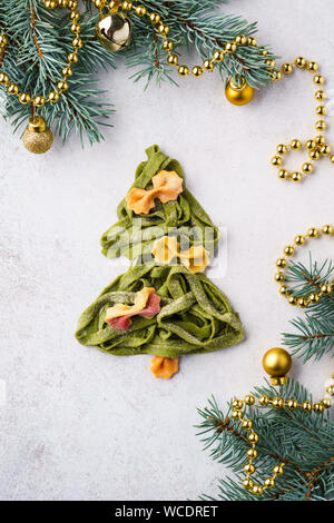 Weihnachtsbaum aus frischen, hausgemachten Spinat Nudeln dekoriert mit bunten Farfalle. Weihnachten Hintergrund. Stockfoto