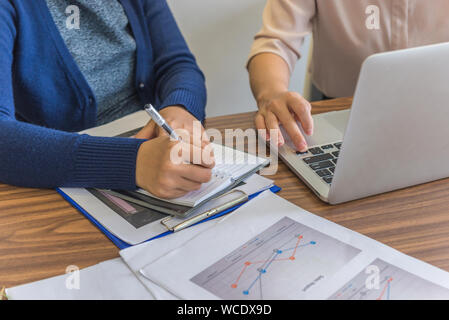 Weibliche Kenntnis nehmen, während die anderen sie auf Laptop Stockfoto