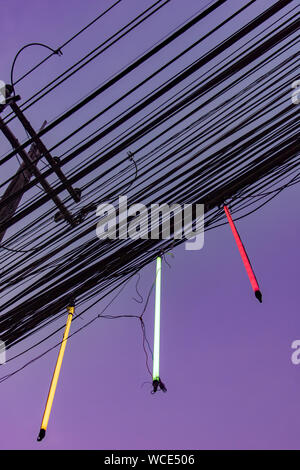 Neonröhren hängen über Power line Kabel. bunter Neonlichter auf die Drähte der Stromleitung angeschlossen die Straße ausleuchten. Stockfoto