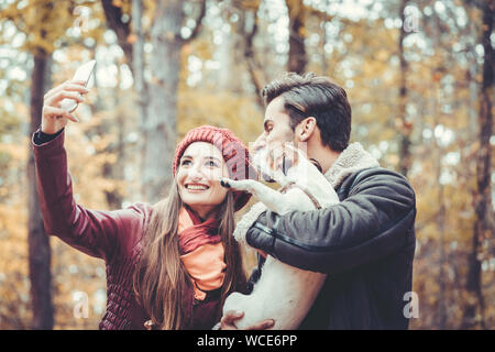 Frau und Mann mit ihren Hund auf Herbst Spaziergang unter einem Telefon selfie Stockfoto