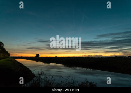 Holländische Landschaft und Himmel in der blauen Stunde. Schöne Farben des Himmels und die Reflexionen in das ruhige Wasser des Kanals. Stockfoto