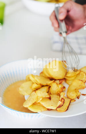 Nahaufnahme von einem kaukasischen Mann in der Küche hinzufügen die Bratkartoffeln, die geschlagenen Eier, zu einem typischen Tortilla de patatas bereiten, ein spanisches Omelette Stockfoto