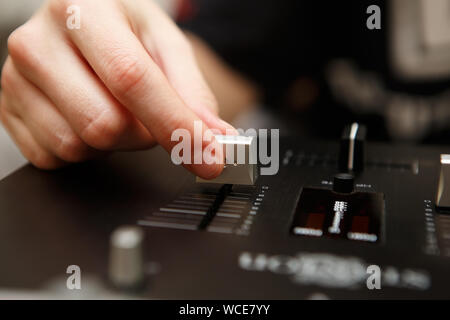 Weibliche Hip Hop DJ spielt Musik in Night Club. Professional Disc Jockey Mädchen wirft musikalische Track Volume auf Sound Mixer Panel. Djs Hand und Regler in f Stockfoto