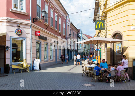 Szent Janos utca Fussgängerzone in Eger, Ungarn mit Menschen am Tisch im Freien von McDonalds sitzen Stockfoto