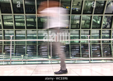 Ein Mann in verschwommene Bewegung am Flughafen in Halle. Abstraktes Bild von Reisenden in der Lobby. Stockfoto