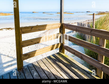 Blick von einer hölzernen Veranda über eine leere Sandstrand bei Ebbe an einem sonnigen Morgen in der Bretagne, Frankreich. Stockfoto