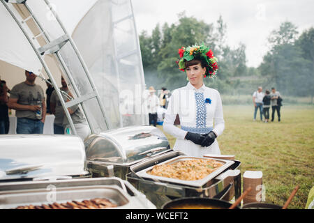 Belaris Minsk 26. 07. 2019 Auf lager Foto Portrait von schöne Frau in traditioneller Folk dress und floralen Kranz auf dem Kopf stehend neben dem Behälter Stockfoto