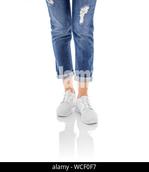 Beine in Jeans und weißen Turnschuhen auf einem weißen Hintergrund. Stockfoto