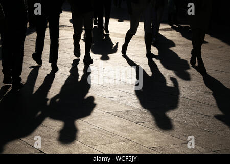 Schwarze Silhouetten und Schatten der Menschen auf der Straße. Menge hinunter auf Bürgersteig, Konzept der Fußgänger, Kriminalität, Gesellschaft, Leben in der Stadt Stockfoto