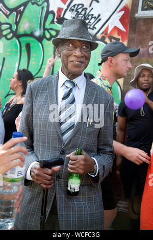 Notting Hill Carnival, 25. August 2019. Eine elegant gekleidete ältere Mann Uhren die Parade. Stockfoto