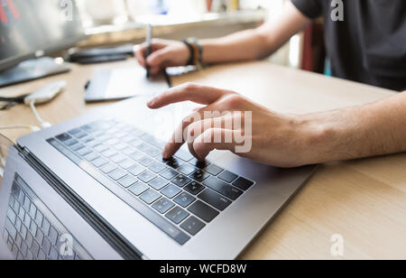 Professionelle foto Retoucher von zu Hause aus arbeiten. Retusche Spezialist arbeitet auf Fotos mit Stylus und Tablet mit modernen Notebooks angeschlossen. c Stockfoto