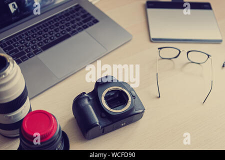 Professional Photo Studio Schreibtisch mit Tools für kreative Fotografen. Große schwarze dslr photocamera, Zoomobjektive, Laptop und Tabelle für die Retusche im Stockfoto