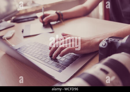 Professioneller Fotograf Retusche von Fotos mit Tablett und Stift in der Hand. Freier Mitarbeiter arbeiten von zu Hause aus. Photo Studio Schreibtisch in Nahaufnahme. Image editor w Stockfoto