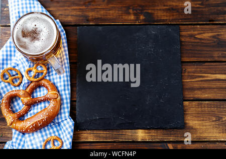 Bierkrug, Brezeln und Würstchen auf Holztisch. Ansicht von oben Stockfoto