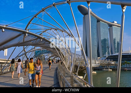 Touristen auf der ikonischen Helix Bridge bis zur Marina Bay Sands Hotel und die angeschlossenen Mall die Geschï¿½te an der Marina Bay Sands, Marina Bay, Singapore Stockfoto