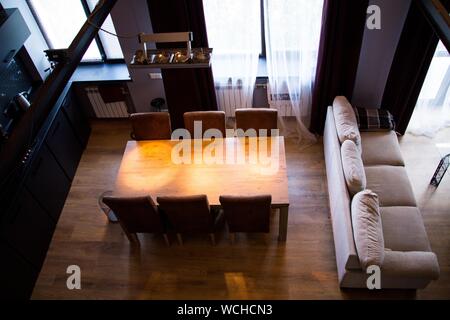 Breite Aufnahme eines Holztisches mit Holzstühlen in der Nähe Ein Sofa in einem Zimmer mit schwarzem Interieur Stockfoto