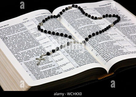 Silberne Kruzifix und Rosenkranz auf offene Bibel Stockfoto