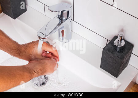 Man wäscht seine Hände in das moderne Bad. Nahaufnahme von Händen und Leitungswasser. Stockfoto