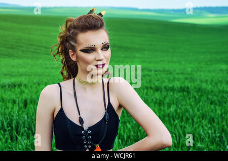 Aggressive Make-up Girl, amazon Charakter in ein grünes Weizenfeld. Feminismus, der Unabhängigkeit, der Stamm. Stockfoto