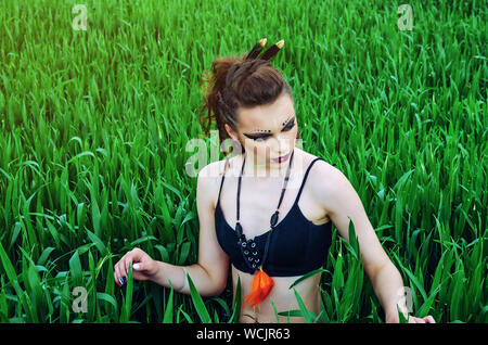 Aggressive Make-up Girl, amazon Charakter in ein grünes Weizenfeld. Feminismus, der Unabhängigkeit, der Stamm. Stockfoto