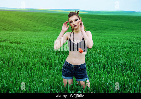 Aggressive Make-up Girl, amazon Charakter in ein grünes Weizenfeld. Feminismus, der Unabhängigkeit, der Stamm. Stockfoto