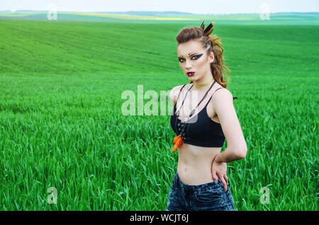 Aggressive Make-up Girl, Schlacht Gemälde des Gesicht von Amazon in einem Feld inmitten grüner Weizen. Feminismus, der Unabhängigkeit, der Stamm. Stockfoto