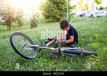 Kind verletzt sein Bein, nachdem sie weg von seinem Fahrrad. Kind ist Lernen ein Fahrrad zu fahren. Junge in der Straße Boden mit einer Knieverletzung schreien nach einem Sturz Stockfoto