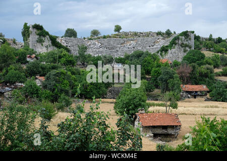 Die Ruinen des antiken Theaters von Selge stand unter den modernen Gebäuden eines kleinen Dorfes. Stockfoto