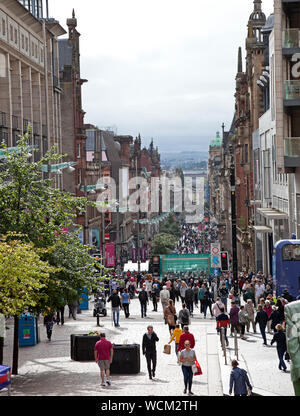 Buchanan Street Glasgow, Schottland, Großbritannien. 28 Aug, 2019. Käufer und Besucher wandern entlang in die dunstige Sonnenschein durch die pedestriansed Buchanan Street in Glasgow. Der Donald Dewar statue stolz an der Oberseite der Straße steht, der erste Minister von Schottland und ein Fürsprecher der Scottish Devolution, würde man mich fragen, was seine Gedanken würden zur heutigen breaking news, dass der britische Premierminister Boris Johnson die Königin gebeten hat das britische Parlament ab Mitte auszusetzen - September. Stockfoto