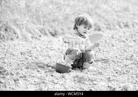 Kleines Kind Einpflanzen einer Blume. Tag der Erde. Böden und Düngemitteln. Sommer Bauernhof. glückliches Kind Gärtner. Blumen Präsentation. Ökologie und Umweltschutz. Landwirtschaft und Landwirtschaft. Stockfoto