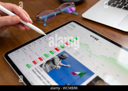 Badewanne, Großbritannien - 28 August, 2019: Ein Apple iPad Pro auf einem Schreibtisch anzeigen Börse Informationen mithilfe des Apple Aktien App. Eine Hand mit einem Apfel Bleistift Stockfoto