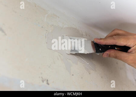 Der Arbeitnehmer umfasst die unebene Wände, die Hände des Menschen mit einem Spachtel und Putty, Appartement Reparatur Stockfoto