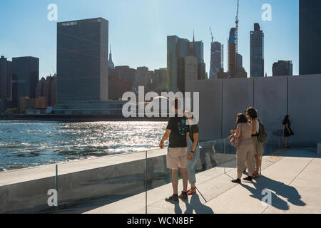 New Yorker Touristen, Blick auf Touristen, die im Four Freedoms Park auf Roosevelt Island stehen und über den East River in Richtung Midtown Manhattan NYC blicken Stockfoto