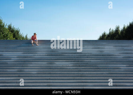 Reife denkende Frau, Blick auf eine Frau mittleren Alters, die auf der monumentalen Treppe im Franklin D Roosevelt Four Freedoms Park, New York City, USA sitzt Stockfoto