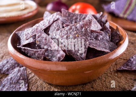 Eine Schüssel mit köstlichen blauen Tortilla corn Nacho Chips in einem authentischen Oaxcan Keramik Schüssel auf rustikalen, mit Holz. Stockfoto