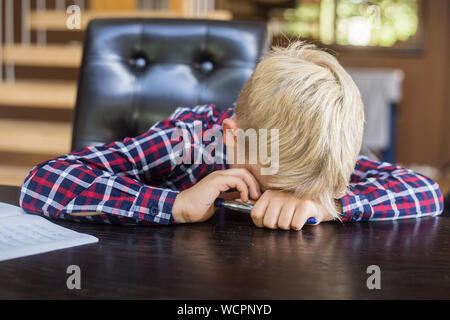 Traurige Schüler schreiben auf Notebook zu Hause. Hausaufgaben. Bildung, Kindheit und Personen Konzept Stockfoto