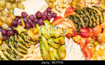 Sortiment von rohen Früchten, Beeren und Brie Käseplatte, Ananas, Birnen, Äpfel, Trauben, Physalis, Karambolen gesundes Essen Konzept Hintergrund Stockfoto