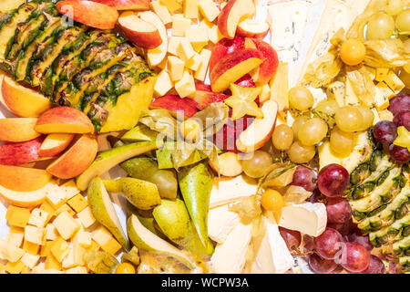 Sortiment von rohen Früchten, Beeren und Brie Käseplatte, Ananas, Birnen, Äpfel, Trauben, Physalis, Karambolen gesundes Essen Konzept Hintergrund Stockfoto