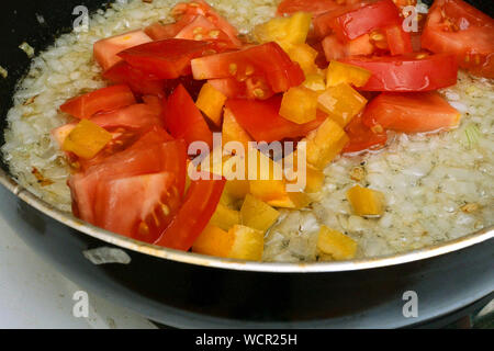 Die Sauce, Dressing für vegetarisches Essen. Frisches Gemüse, Tomaten, Zwiebeln, Pfeffer, gebraten und gemischt in einer tiefen Pfanne Braten mit Speiseöl Stockfoto