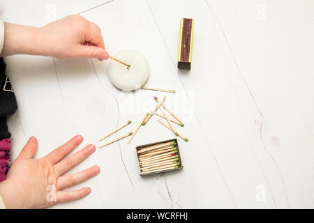 Nahaufnahme der Kinder mit dem Feuer spielen, Streichhölzer und eine Kerze auf Home Zimmer Etage. Brandgefahr zu Hause Konzept. Stockfoto