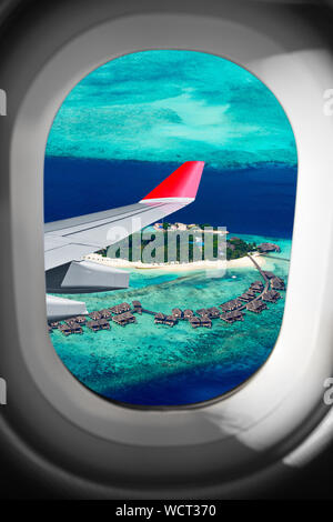 Blick durch Flugzeug Fenster fliegen Flügel vor der tropischen Insel im Indischen Ozean Malediven. Transport Ferienhäuser Flugreisen fly Conc Stockfoto