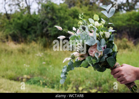 Hand, die einer Frau, die eine Hochzeit Blumenstrauß mit frischen weißen und rosa Blüten Stockfoto