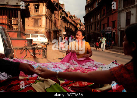 Eine Frau kaufen Bezüge von einem Verkäufer, in Patan, auch als Lalitpur (Stadt der Schönheit), Nepal bekannt. 2010. Stockfoto