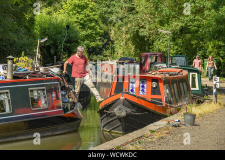 BATH, ENGLAND - Juli 2019: Person Stepping über, ein Boot beim an einem schmalen Boot auf dem Somerset Kohle Canal in der Nähe der Stadt Bath Stockfoto